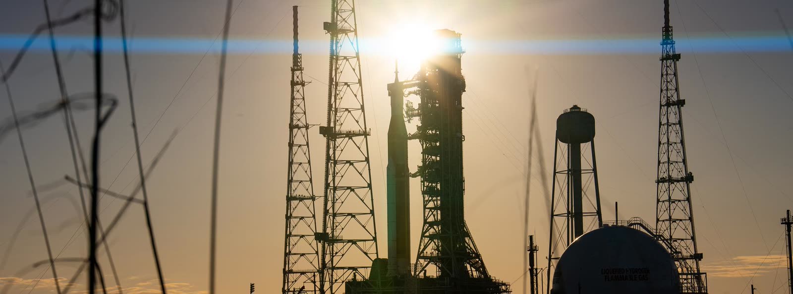 A rocket standing on its launch pad at sunset, held in the service structure, waiting to fly.